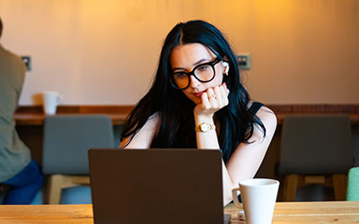 A woman with glasses looking at a laptop computer